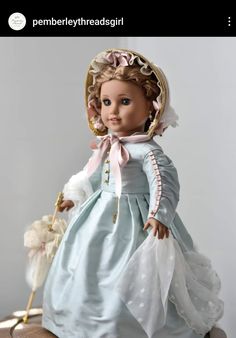 the doll is wearing a blue dress and hat