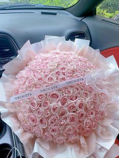 a bouquet of pink roses is sitting in the front seat of a car with a name tag on it