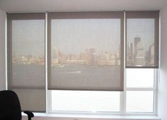 an office window with blinds in front of the cityscape, and a chair