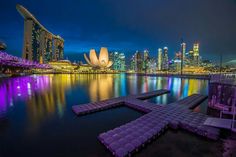 the city skyline is lit up at night with lights reflecting in the water and buildings