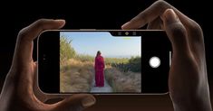 someone taking a photo with their phone of a woman in a red dress on a path