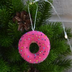 a pink donut ornament hanging from a christmas tree