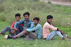 four young men are sitting on the grass