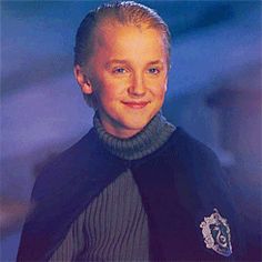 a young boy with blonde hair wearing a star trek uniform and smiling at the camera