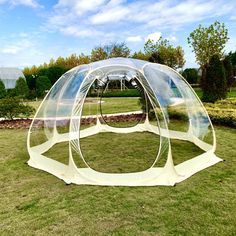 an inflatable bubble tent sitting on top of a lush green field