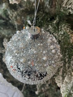 a glass ornament hanging from a tree with snow flakes on the branches