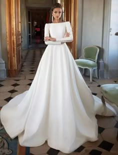 a woman in a white wedding dress standing in a hallway