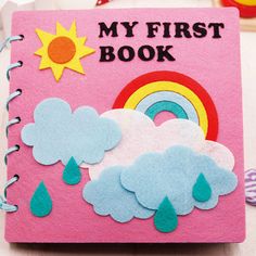 a pink book with felt clouds and rainbows on it, sitting on a table