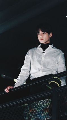 a young man in a white shirt and black tie standing at the top of a railing