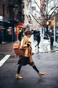 a woman walking down the street carrying a brown bag