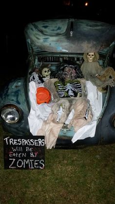 an old car with skeletons and other items in the trunk that says trespassers will be eaten by zombies