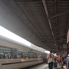 people are waiting for the train to arrive at the station in this photo, there is a man walking on the platform