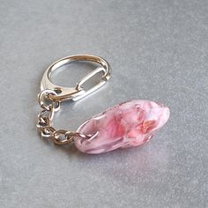 a pink piece of jewelry sitting on top of a gray table next to a pair of scissors