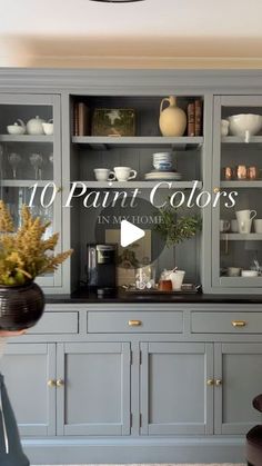 a woman standing in front of a gray china cabinet