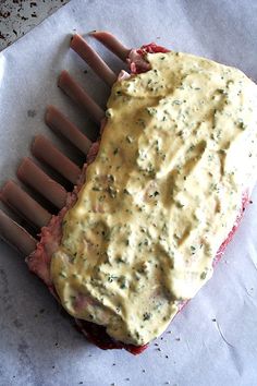 a piece of meat with sauce on it sitting on top of wax paper next to a knife