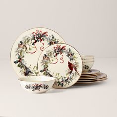 a set of christmas dinnerware with holly wreaths and birds on the rim,