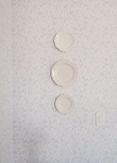 three white plates are hanging on the wall