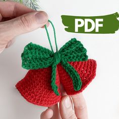 a hand holding a crocheted strawberry ornament with green leaves on it