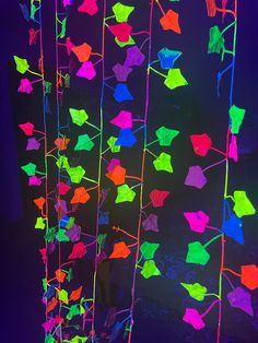 brightly colored paper stars hanging from strings in the dark, lit up by neon lights