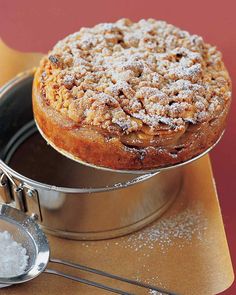 a cake sitting on top of a metal pan next to a scoop of powdered sugar