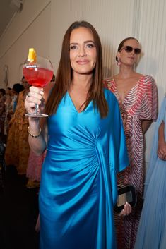 a woman in a blue dress holding a drink