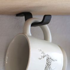 a coffee cup hanging from a wooden shelf