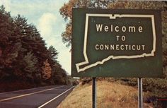 a welcome to connecitut sign on the side of a road with trees in the background