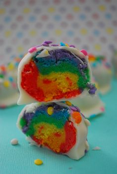 rainbow truffles with white frosting and sprinkles on blue background