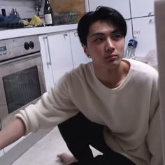 a young man sitting on the floor in front of an oven