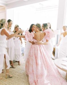 a group of women in white dresses standing next to each other and one woman wearing a pink dress