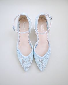 a pair of blue shoes with white lace on the toes and heel, sitting on a light colored surface