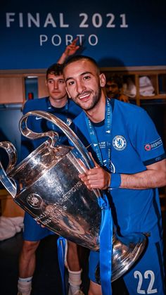 two soccer players are holding up the trophy