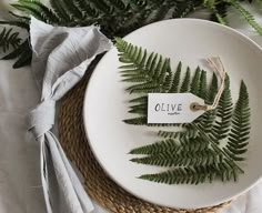 a white plate topped with a green fern leaf and a tag that says olive on it