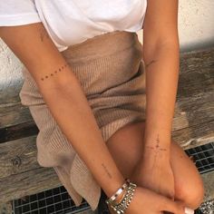 a woman sitting on top of a wooden bench with her arm tattoos tattooed above her left leg