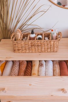 a basket filled with lots of different items on top of a wooden shelf next to a mirror