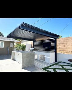 an outdoor kitchen and grill area in a backyard