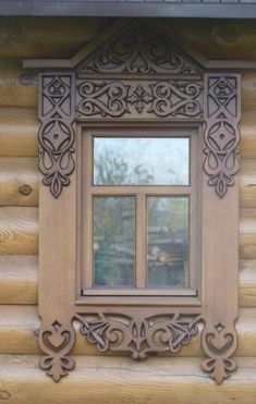 a wooden window on the side of a log cabin with an intricate design around it