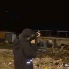 a man standing in front of a pile of trash holding a cell phone to his ear