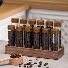 several bottles filled with coffee beans on top of a wooden stand next to a spoon