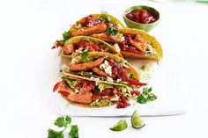 three tacos on a plate with salsa and guacamole