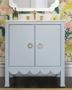 a bathroom vanity with an oval mirror above it and flowers on the wall behind it