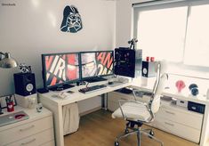 a computer desk with two monitors on top of it next to a white chair in front of a window