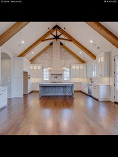 a large open kitchen with white cabinets and wood beams on the ceiling is shown in this image