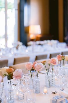 A wedding table centerpiece made of hundreds of bud vases, each cradling a rose in a palette of pale and blush pinks Bridal Shower Bud Vases, Simple Rose Table Centerpieces, Bud Vases Roses, Bud Vases With Roses, Wedding Table Centerpieces Vases, Pink Bud Vases Wedding, Rose Bud Vase Centerpiece, Single Rose Bud Vase Centerpieces