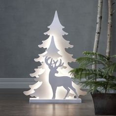 a lighted christmas tree with a deer standing next to it