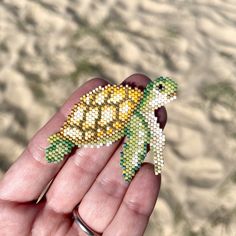 a hand holding a small beaded turtle in it's palm