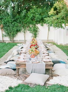 a long table is set up in the middle of a yard with flowers on it