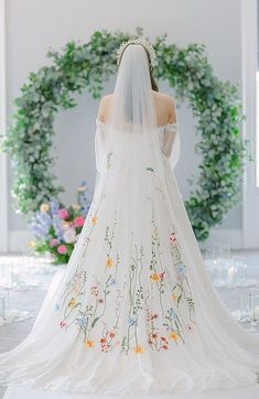 a woman in a white wedding dress with flowers on the back and veil over her head