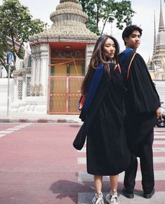 two people in graduation gowns standing next to each other