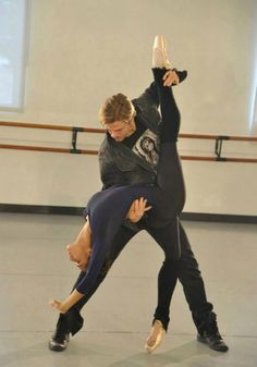 two people are doing an acrobatic move in a dance studio, one is holding the other upside down